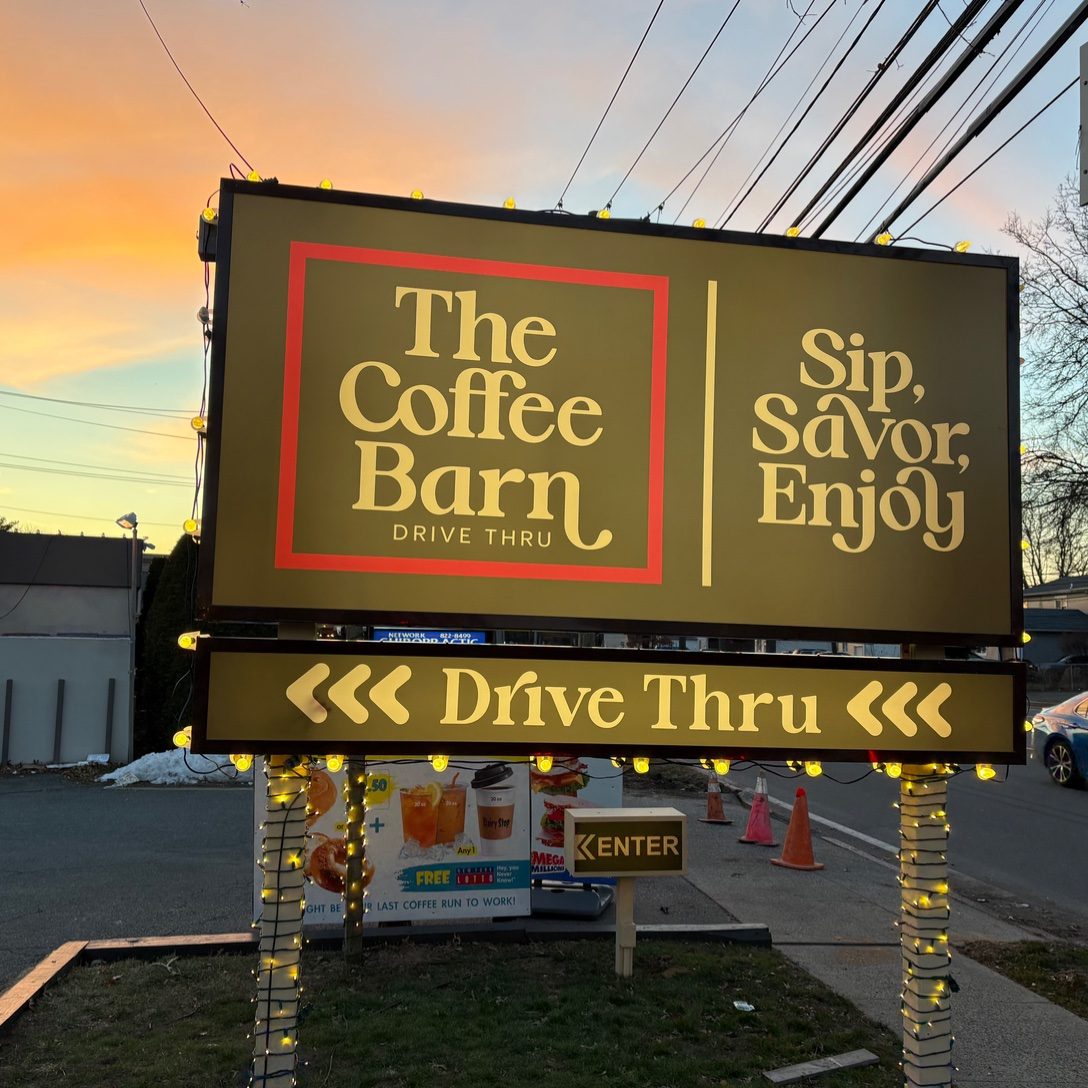 The original Coffee Barn sign glowing at sunset on Old Country Road